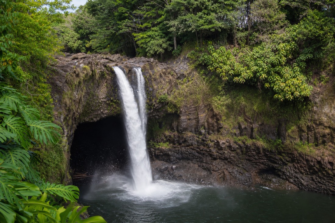 Rainbow Falls pouring over a lava ledge into a pool near downtown Hilo on a bright morning
